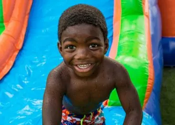 Smiling boy enjoying a colorful inflatable water slide rental