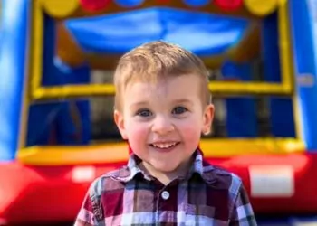 Happy toddler standing in front of an inflatable bounce house in Winter Haven